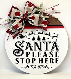 a sign that says santa please stop here with a bow on the front and bottom