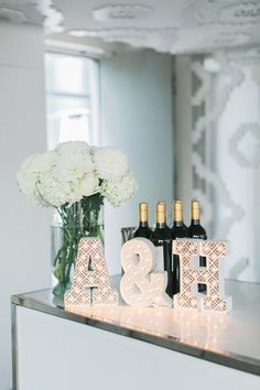 an image of a table with bottles of wine and flowers on it, which are decorated with letters that spell out the word'a & b & h