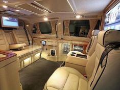 the interior of a luxury vehicle with leather seats and televisions on either side of the car