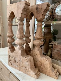 a wooden clock sitting on top of a white counter next to a dresser and mirror