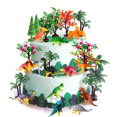 a three tiered cake decorated with dinosaurs and trees