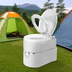 an open toilet sitting on top of a field next to a tent and camping equipment