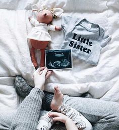 a woman laying on top of a bed next to a baby doll and an album