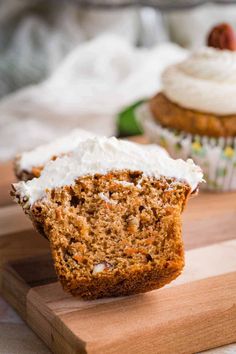 two carrot cupcakes with frosting on a cutting board