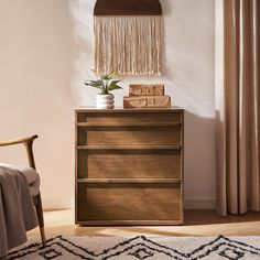 a wooden dresser sitting next to a chair in a room with curtains and a rug on the floor