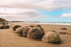 large rocks sitting on top of a sandy beach