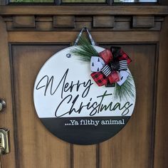 merry christmas ya filthy animal sign hanging on the side of a door with pine branches