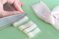 someone is cutting fish with a knife on a green counter top next to pieces of meat