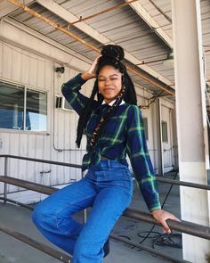 a young woman is posing for the camera wearing jeans and a plaid shirt with braids on her head