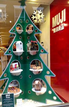 a green christmas tree in the window of a shoe store with shoes on display and snowflakes hanging from it's sides