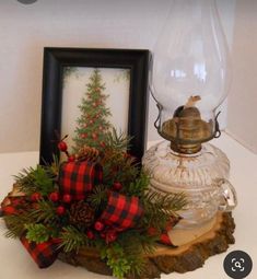 a small christmas tree in a glass vase on top of a wooden stump with a bow