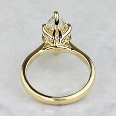 a yellow gold engagement ring with three pear shaped diamonds on the side, set in 18k yellow gold