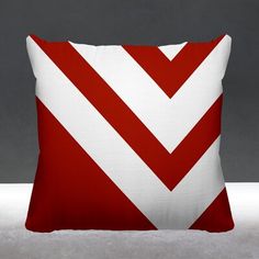 a red and white pillow sitting on top of a gray floor next to a wall