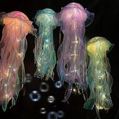 three jellyfish lights hanging from strings with bubbles in the water behind them on a black background