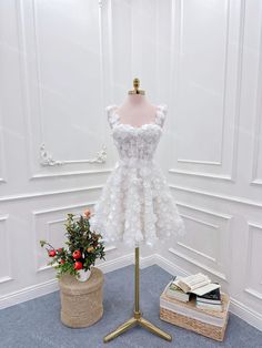 a white dress on display next to a flower pot