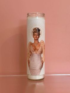 a candle with an image of a woman wearing a bra and angel wings on it