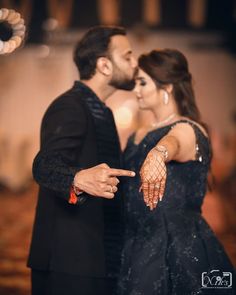 a man and woman standing next to each other in front of a stage with lights