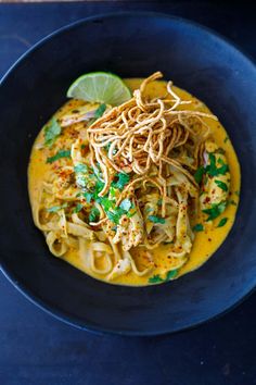 a black bowl filled with noodles and garnished with cilantro