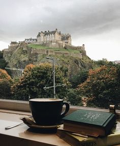 a cup of coffee sitting on top of a window sill next to a book