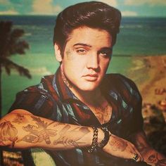 a young man with tattoos on his arm and arms is posing for a photo in front of the ocean