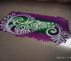 a purple and green painting on the ground in front of a window with white swirls