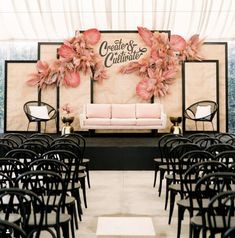 a room filled with lots of black chairs next to a wall covered in pink flowers