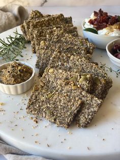 some granola bars are sitting on a plate with bowls of yogurt and other toppings