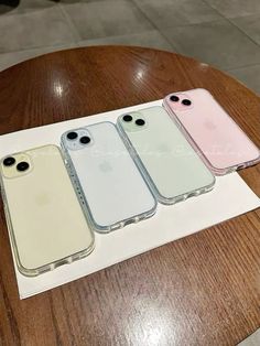 three iphones sitting on top of a wooden table next to each other in different colors