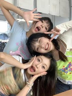 three young women standing next to each other with their hands in the air and smiling