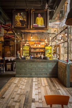 the inside of a restaurant with wooden floors and pictures hanging from the ceiling above it