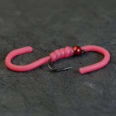 a pair of pink fishing hooks sitting on top of a stone floor next to a hook