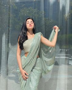 a woman in a green sari posing with her hands on her hips and eyes closed