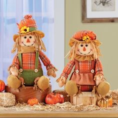 two scarecrows sitting on hay with pumpkins