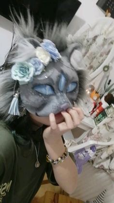 a woman wearing a cat mask with flowers on her head and hair in front of her face