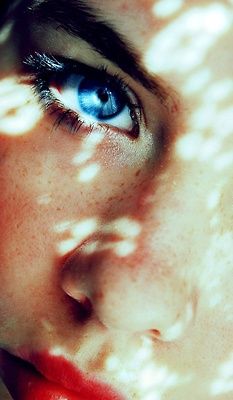 a woman's face with blue eyes and freckles on her skin, looking directly into the camera