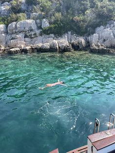 a person swimming in the water near some rocks