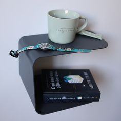 a coffee cup sitting on top of a table next to a book and a watch