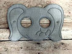 an elephant mask with two holes in the middle on a wooden surface and wood planks behind it