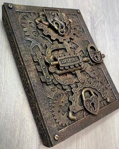 an old metal book with ornate designs on the front and back cover, sitting on a white surface