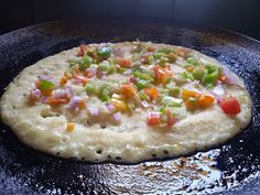 an uncooked pizza sitting on top of a frying pan covered in cheese and veggies