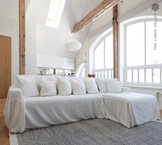 a large white couch sitting in the middle of a living room next to a window