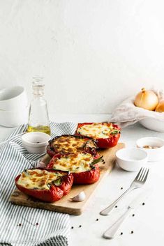 three stuffed tomatoes on a wooden cutting board