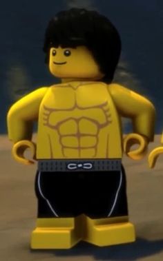 a lego man standing on top of a beach next to the ocean with his hands in his pockets