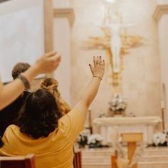 two people raising their hands in front of the alter at a catholic church during a service