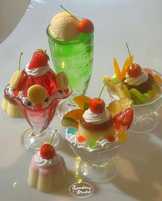 three small desserts in glass bowls with fruit on top and icecream behind them