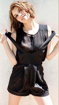 a woman posing with her hands in the air while wearing a short black romper