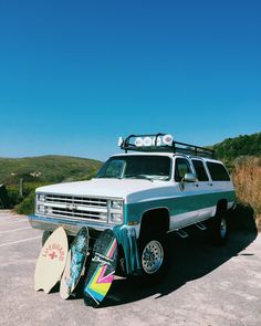 a truck with surfboards attached to it parked in a parking lot next to mountains