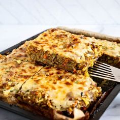 a pan filled with lasagna casserole next to a fork