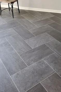 a wooden bench sitting on top of a gray tile floor next to a white wall