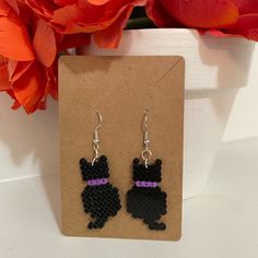 a pair of black and purple earrings sitting on top of a card